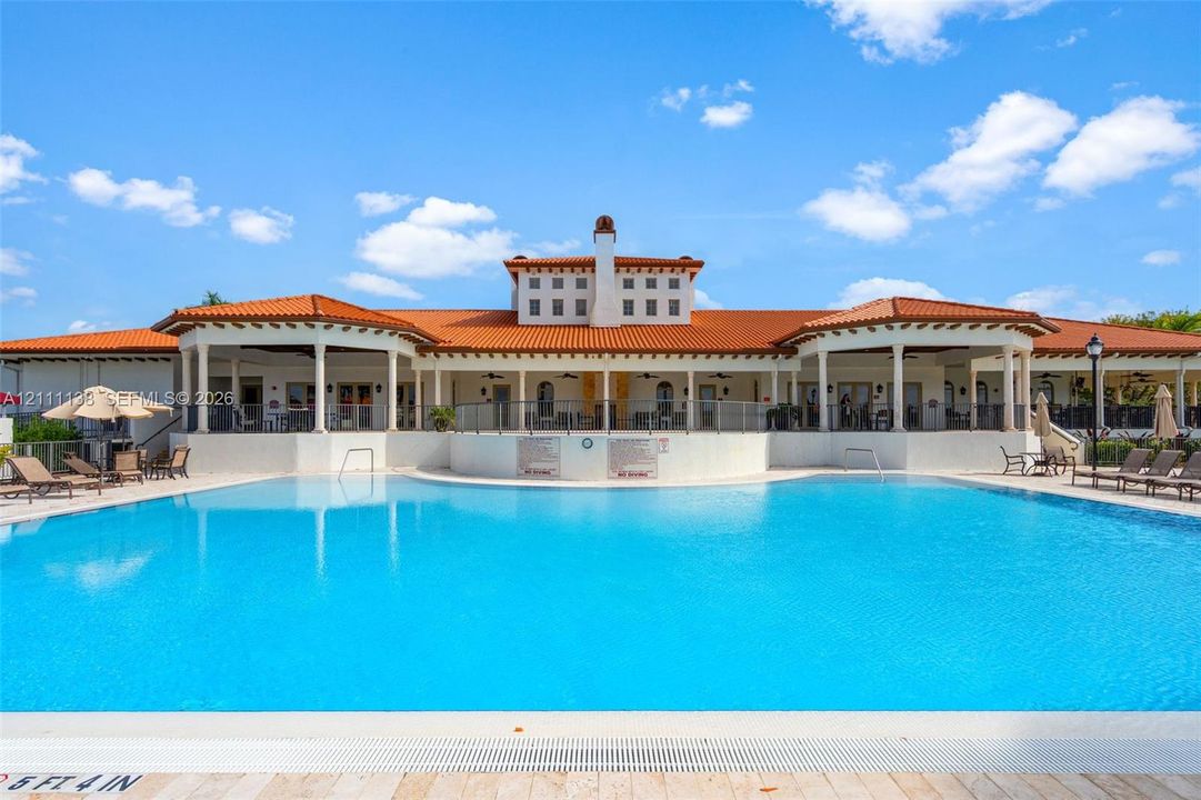 Swimming pool with paved surround, covered terrace, and Mediterranean-style architecture featuring a tile roof