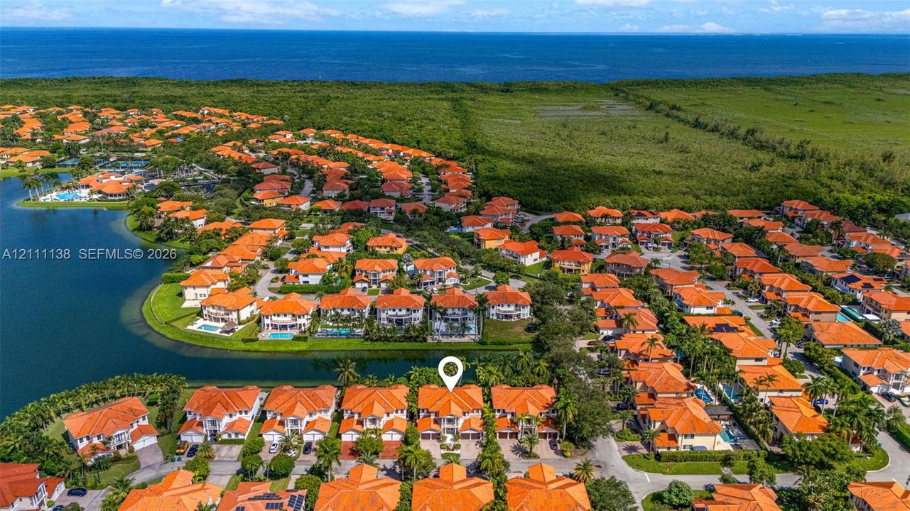 Aerial perspective of a multi-level residence featuring a clay tile roof, paved driveway, and water frontage with bulkhead