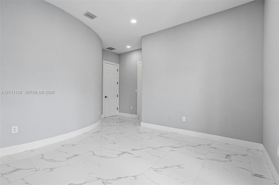 Interior space featuring polished large-format tile flooring with veining, curved wall architecture, and recessed ceiling lighting