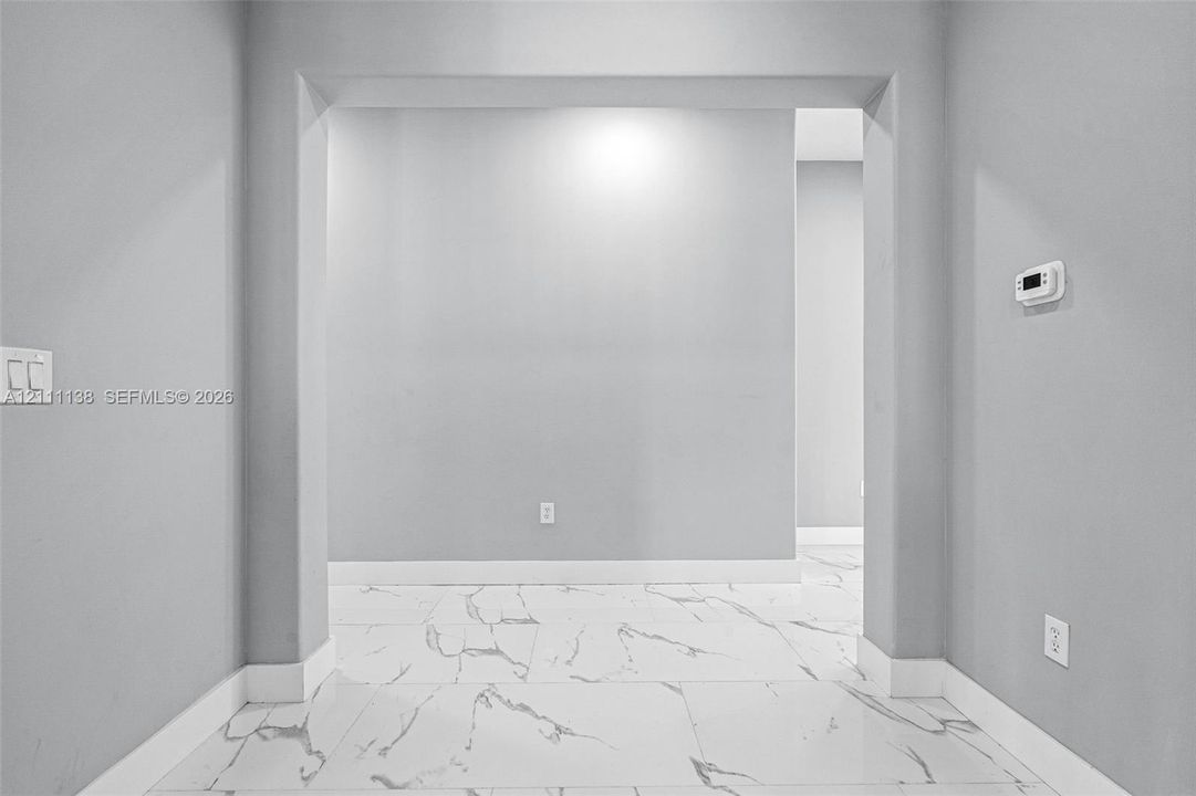 Large-format tile flooring featuring high-contrast veining, neutral grey wall paint, and a wide architectural archway