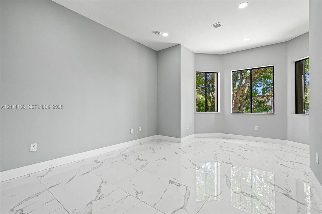 Polished tile flooring with marble-patterned veining, recessed lighting, and a bay window configuration