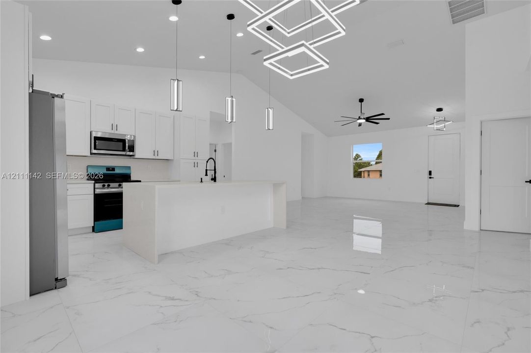 Kitchen with off-white cabinetry, stainless steel appliances, and pendant lighting over the island.