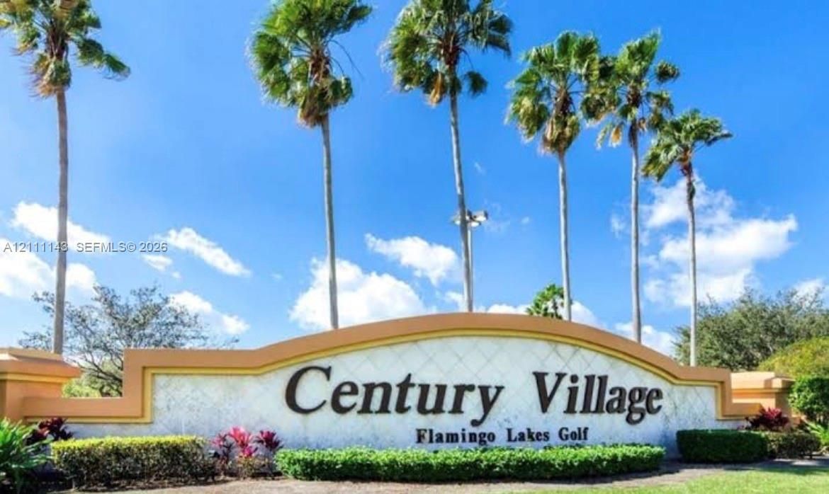 Entry signage featuring decorative masonry, relief detailing, and mature palm landscaping