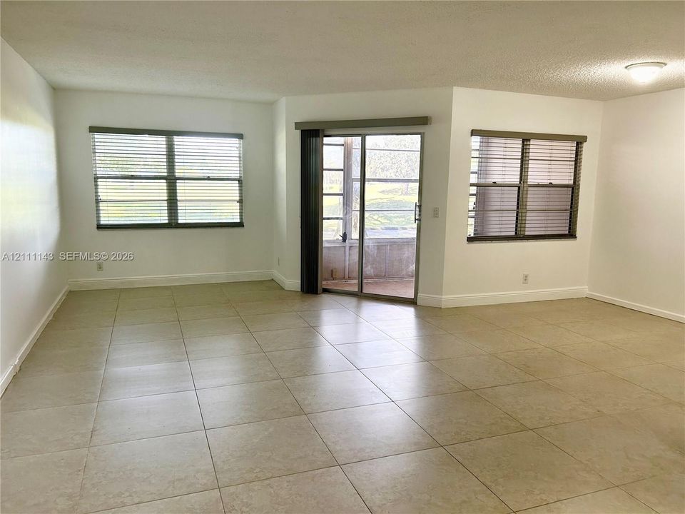 Interior space featuring large-format ceramic tile flooring, neutral wall finishes, multiple windows, and sliding glass doors