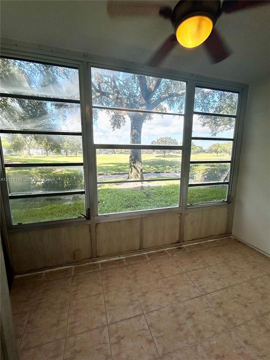 Enclosed space featuring ceramic tile flooring, a mounted ceiling fan, and large horizontal sliding windows showcasing exterior greenery