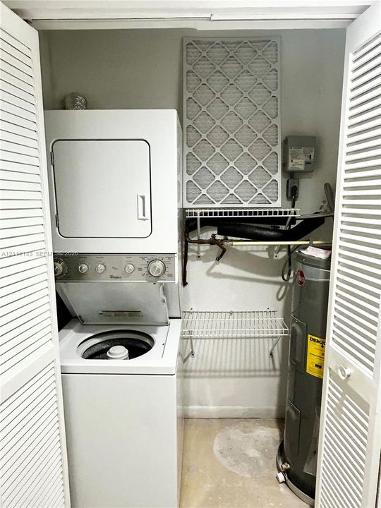 Stacked laundry unit, white louvered bifold closet doors, and wire shelving