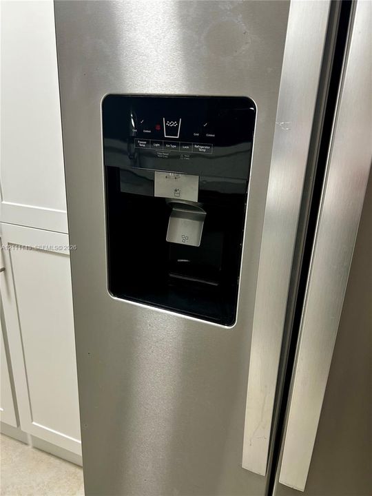 Stainless steel refrigerator featuring an external water and ice dispenser with a digital interface