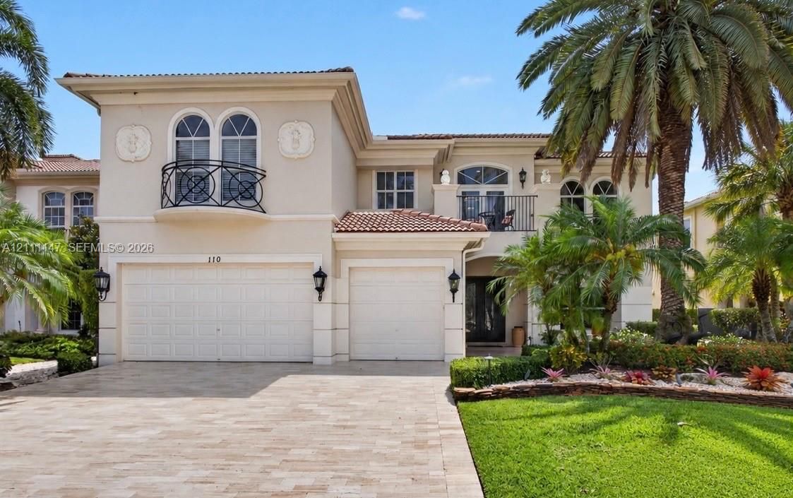 Two-story stucco exterior featuring arched windows, wrought-iron balconies, a tile roof, and a multi-car garage with paver driveway