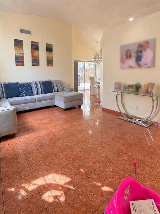 Living area featuring vaulted ceilings, oversized tile flooring, and a large sliding glass door