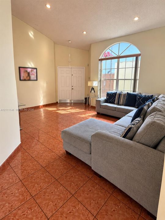 Vaulted ceilings, arched window with grid detail, double-entry doors, and high-gloss tile flooring