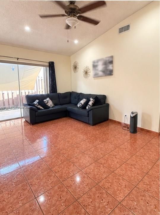 Room featuring vaulted ceilings, oversized ceramic tile flooring, and a ceiling-mounted light fixture with a fan