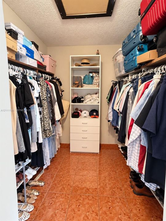 Walk-in closet featuring floor-to-ceiling shelving, built-in drawer storage, dual-sided hanging rods, and ceramic tile flooring
