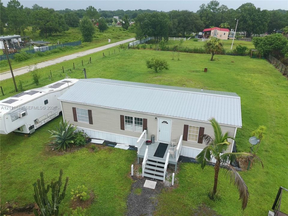 Single-story residence featuring a metal roof, vinyl siding, shutter-framed windows, and an elevated wooden entry deck