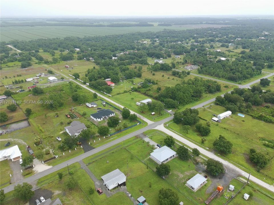 Aerial perspective featuring extensive land area, mature tree clusters, and paved road access
