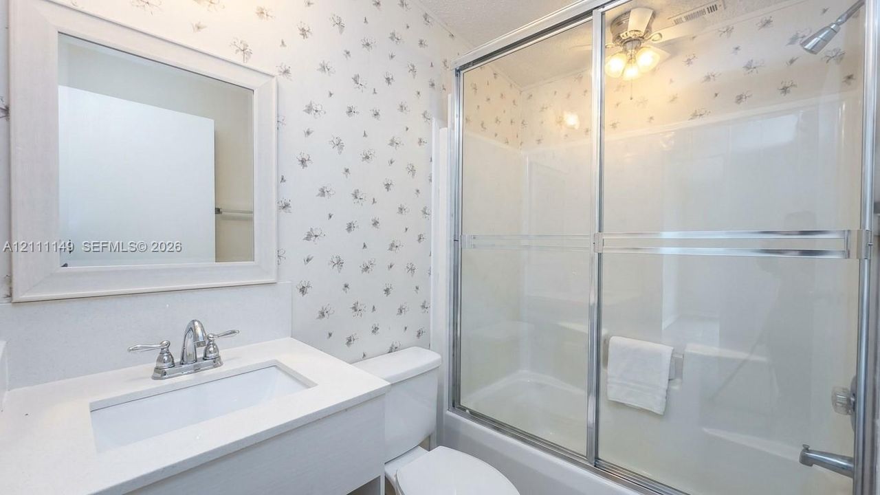 Bathroom featuring a vanity with a white countertop and integrated sink, framed wall mirror, and a tub-shower combination with sliding glass doors