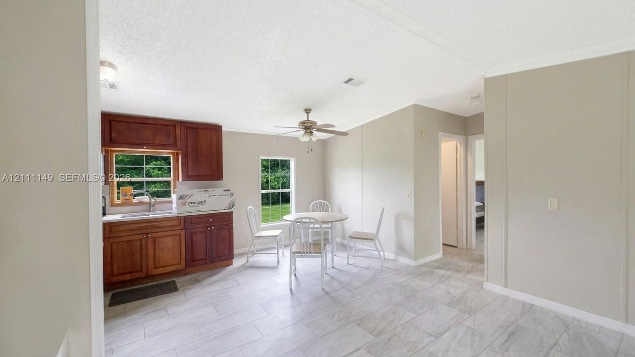 Kitchen featuring wood cabinetry, tiled flooring, dual windows, and a ceiling fan