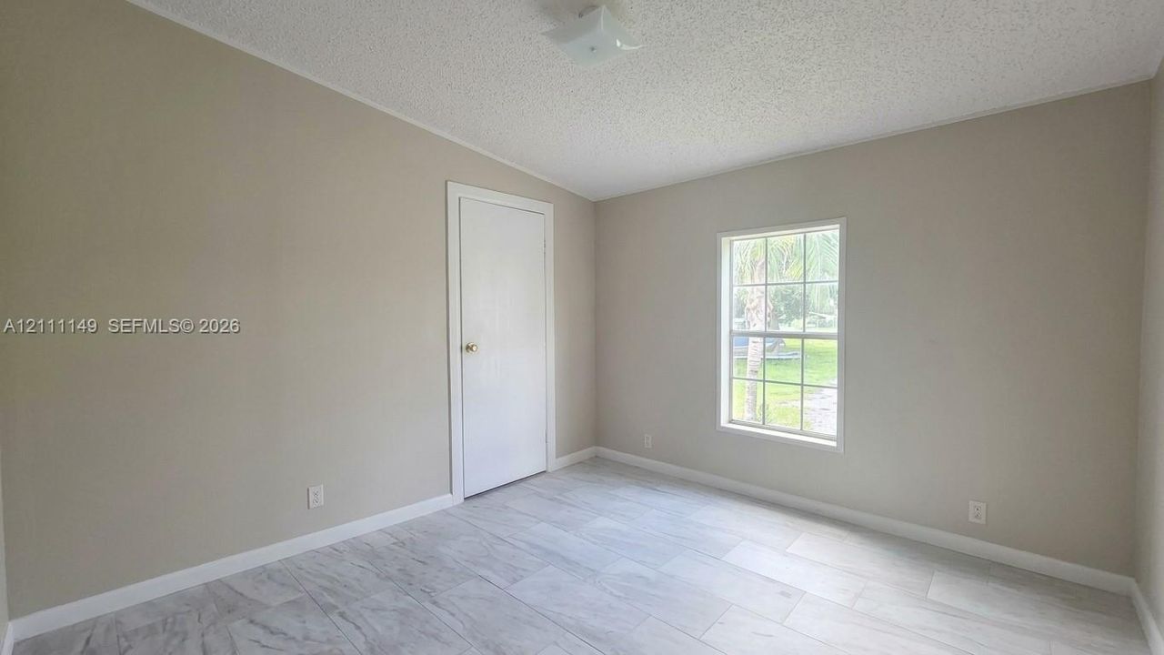 Interior space featuring neutral wall paint, multi-pane window, flush-mount ceiling light, and stone-finish flooring