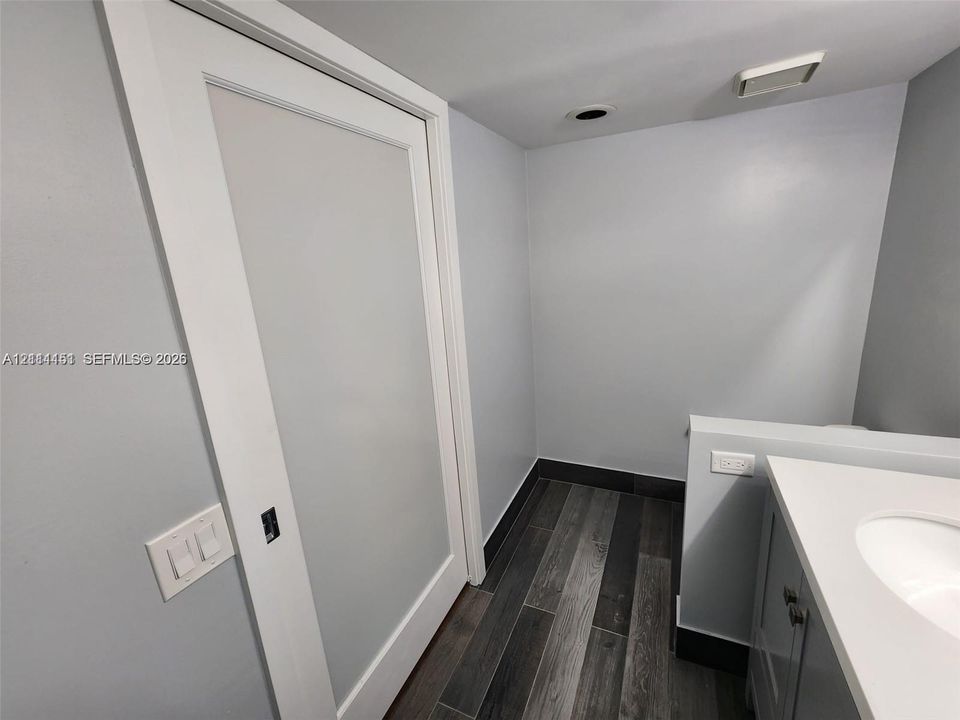 Interior space featuring wood-finish flooring, a white vanity with an integrated sink, and a white paneled sliding pocket door