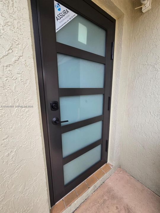 Modern exterior door featuring a dark metal frame, five horizontal frosted glass panels, and matte black lever hardware