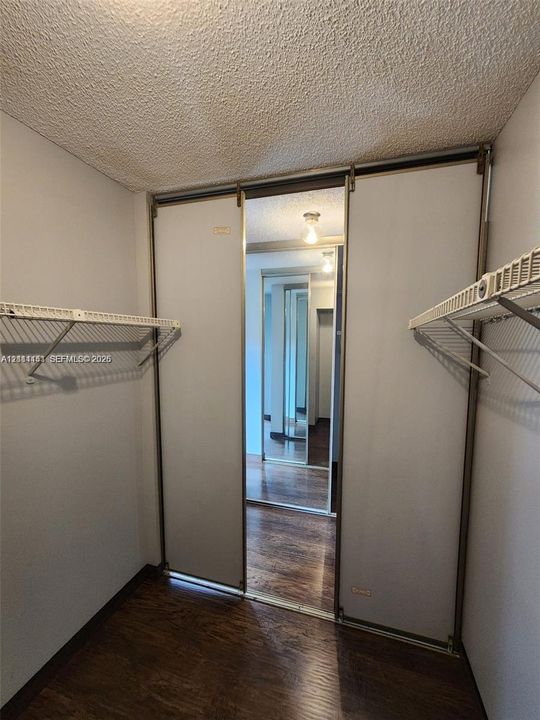 Closet featuring wire shelving and sliding mirrored doors with metal framing, finished with wood-finish flooring