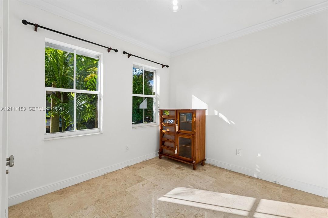 Natural stone flooring, double-hung windows, crown molding, and metal curtain rods
