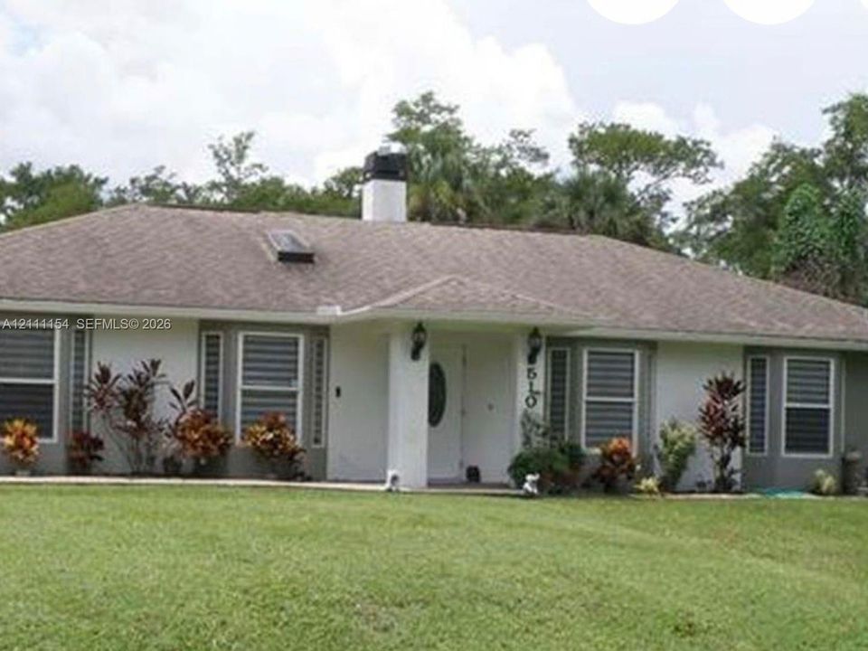 Single-story exterior featuring a hip roof, chimney stack, skylight, and multi-paned windows with decorative framing