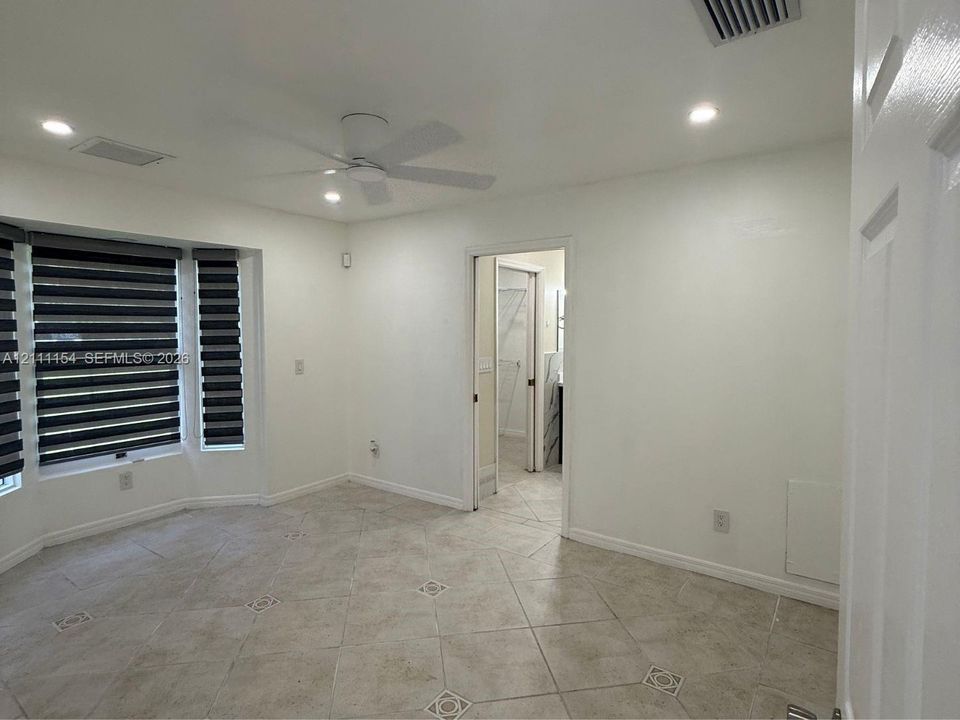 Room featuring bay windows, tile flooring with decorative inlay, recessed ceiling lighting, and a modern ceiling fan