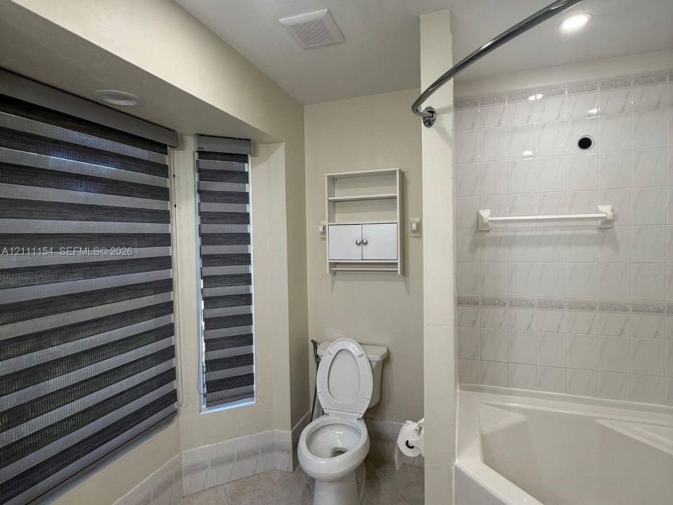 Bathroom featuring a soaking tub with tiled surround, bay window, and built-in wall cabinetry