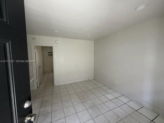 Interior space featuring neutral wall paint, recessed lighting, and square tile flooring