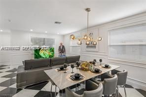 Dining area featuring multi-globe chandelier lighting, wainscoting wall paneling, and black-and-white checkered tile flooring