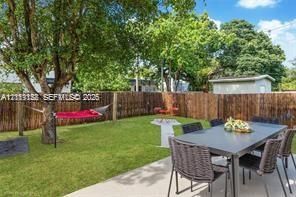 Private backyard featuring a concrete patio, wood-slat privacy fencing, a manicured lawn, and mature trees