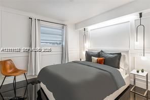 Interior space featuring wall paneling, high-gloss flooring, horizontal blinds, and dual custom pendant light fixtures