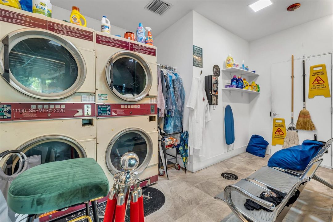 Laundry area featuring dual stackable washer-dryer units, tile flooring, and wall-mounted shelving