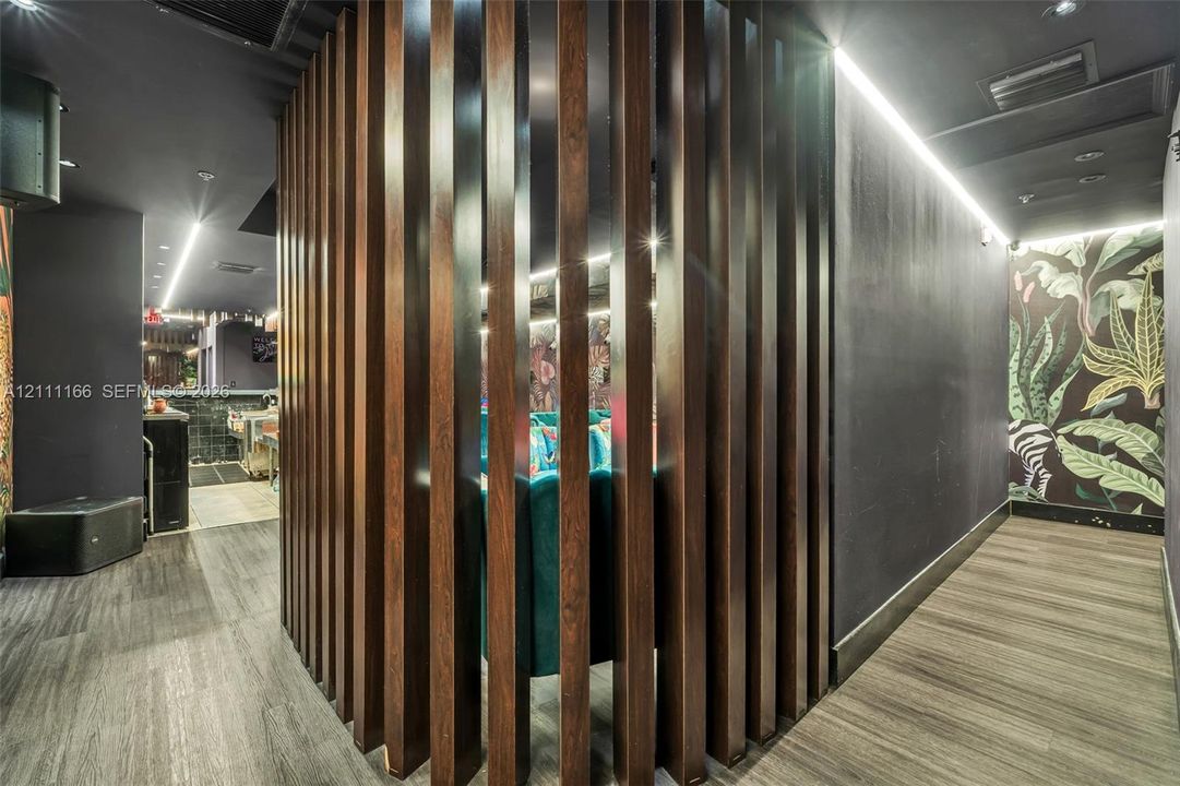Custom vertical wood slat architectural partition, recessed linear ceiling lighting, dark-toned interior wall finishes, and patterned wall covering
