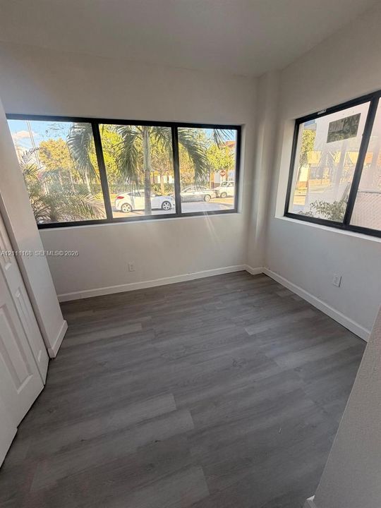 Room featuring wood-finish flooring, multi-pane windows with black frames, and a paneled closet door