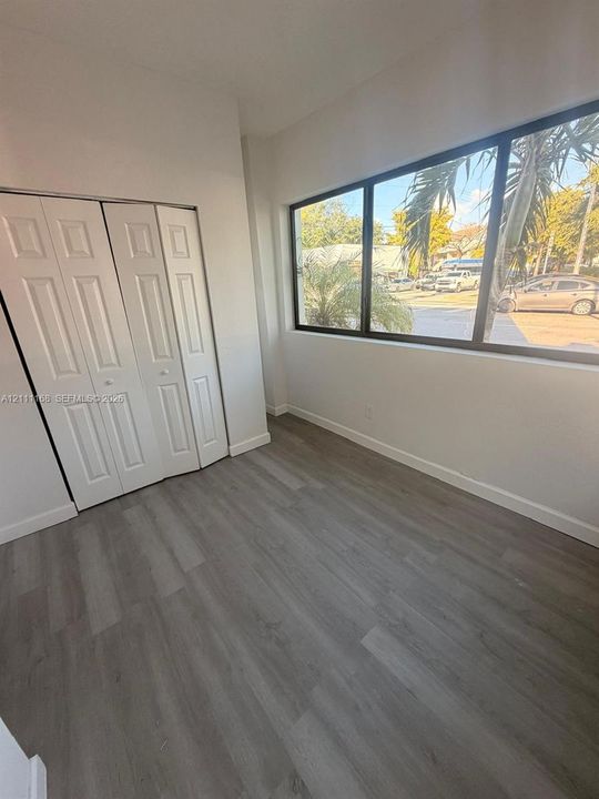 Interior space featuring wood-finish flooring, a multi-panel closet with white paneled doors, and an expansive window with black framing