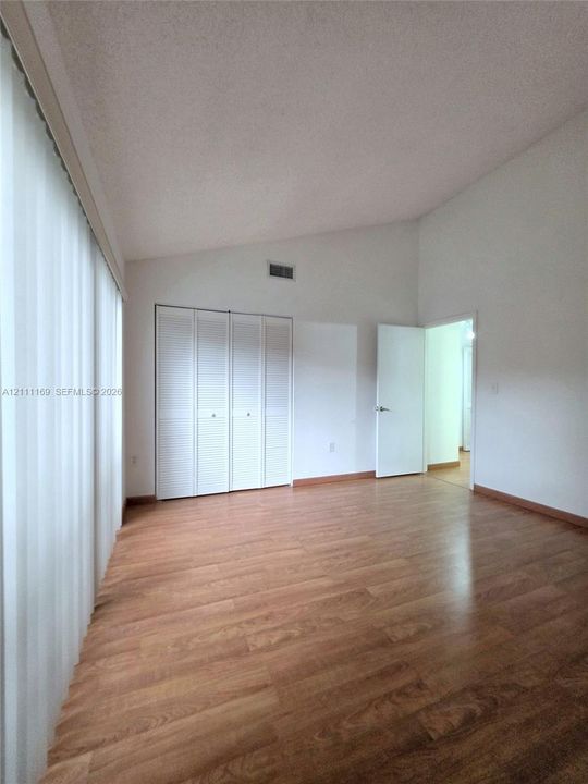 Sliding glass door opening to a private concrete balcony featuring a dark metal railing and wood-finish flooring