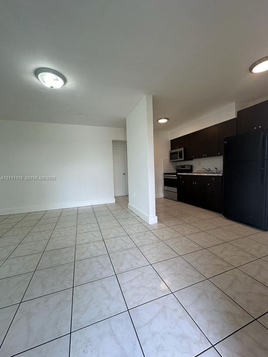 Ceramic tile flooring, dark cabinetry, and black appliances including a refrigerator, oven, and built-in microwave