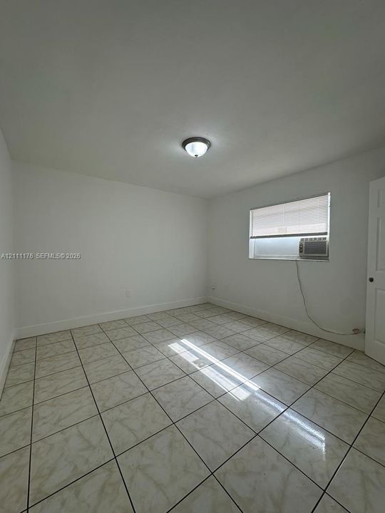 Neutral-toned tile flooring, flush-mount ceiling lighting, and a window with integrated blinds