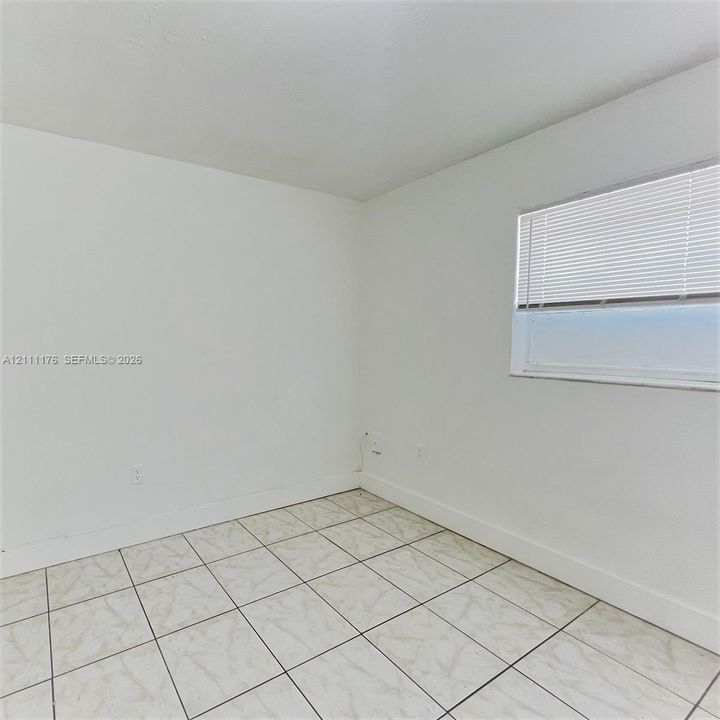 Neutral-toned ceramic tile flooring paired with a single-pane window featuring horizontal blinds