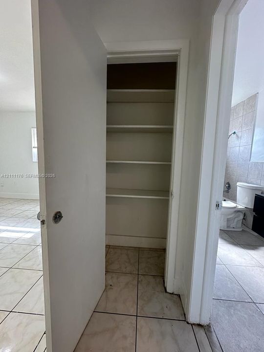 Storage closet featuring built-in shelving, complemented by ceramic tile flooring throughout the area