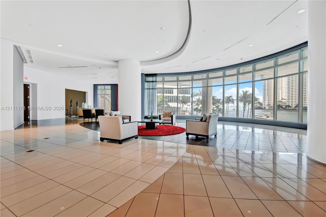 Expansive open-concept floor plan featuring polished tile flooring, recessed lighting, curved ceiling architectural detail, and floor-to-ceiling windows