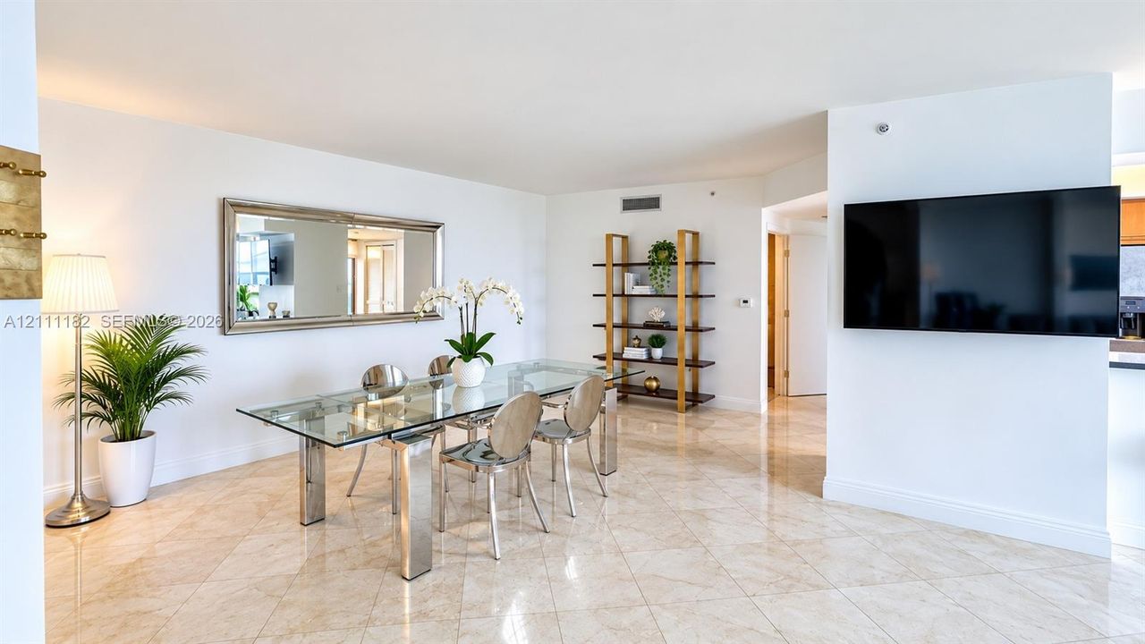 Open-concept dining area featuring polished stone tile flooring, neutral wall finishes, and a decorative wall-mounted mirror