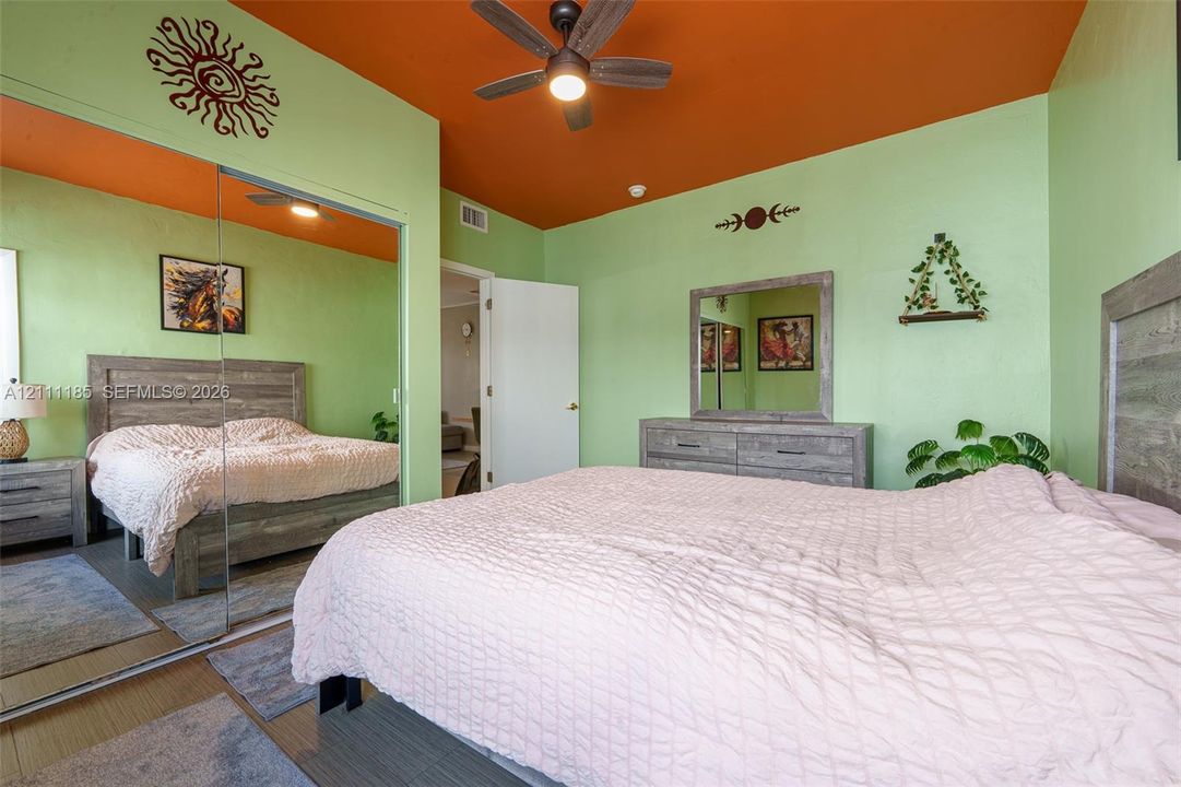 Room featuring mirrored closet doors, a ceiling fan with light fixture, and textured wall surfaces