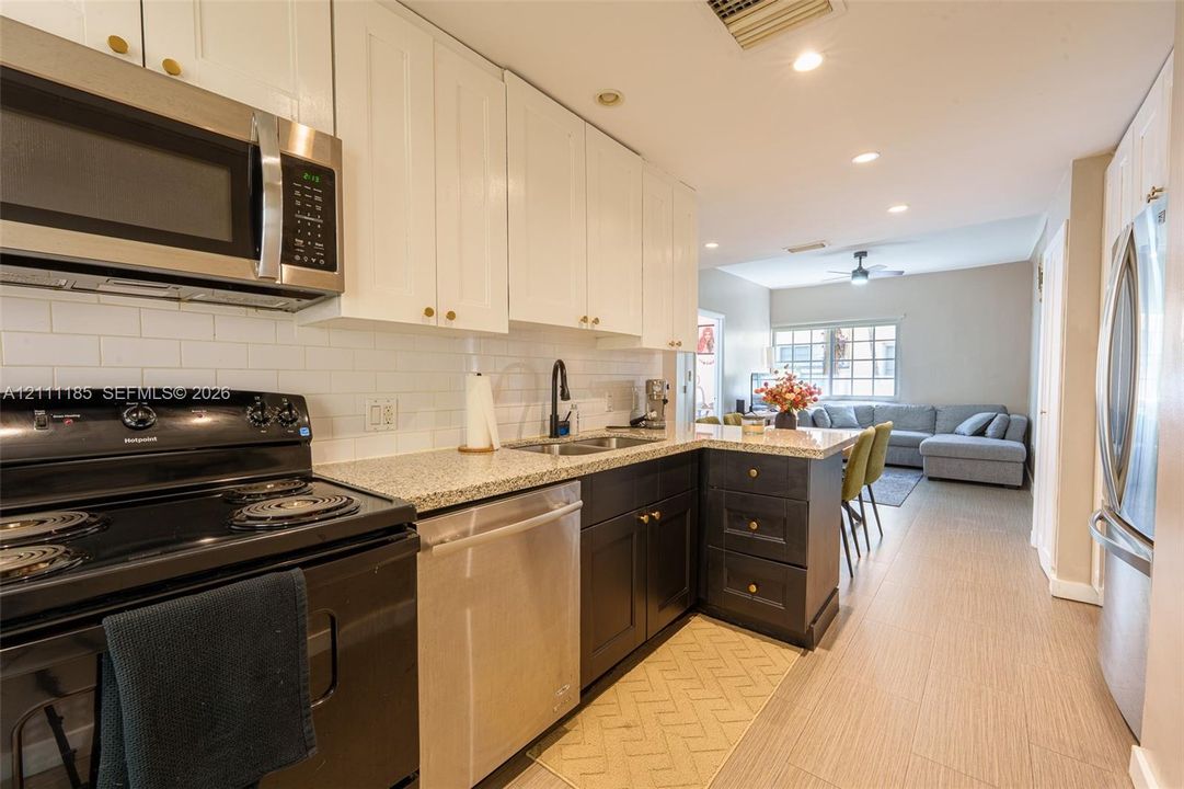 Kitchen featuring two-tone cabinetry, stone-finish countertops, white subway tile backsplash, stainless steel appliances, and recessed lighting