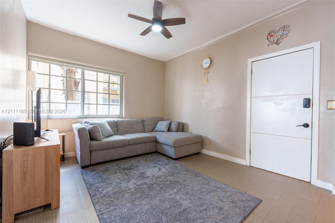 Wood-finish tile flooring, multi-pane window, modern multi-panel interior door, and a ceiling fan with integrated lighting