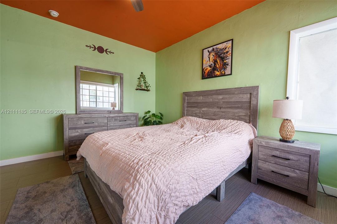 Room with wood-finish flooring, ceiling fan, and window with white trim