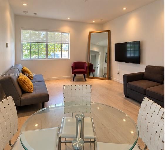 Light-toned wood-finish flooring, recessed lighting, and a multi-pane window with a roller shade