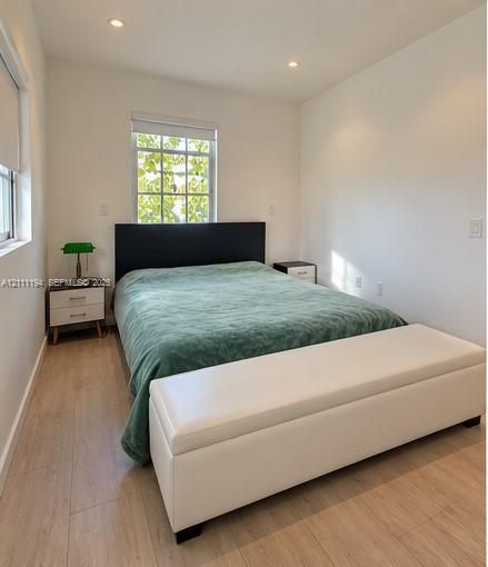 Neutral-toned room featuring light-toned wood-finish flooring, recessed lighting, and dual multi-pane windows with integrated blinds