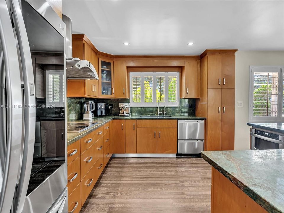 Kitchen featuring natural wood cabinetry, stainless steel appliances, stone countertops, integrated range hood, and wood-finish flooring